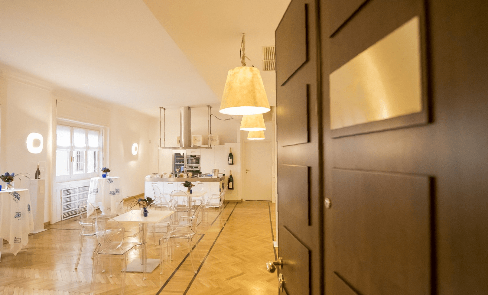 Bright event room at Spazio Pio XI with tables and an open kitchen