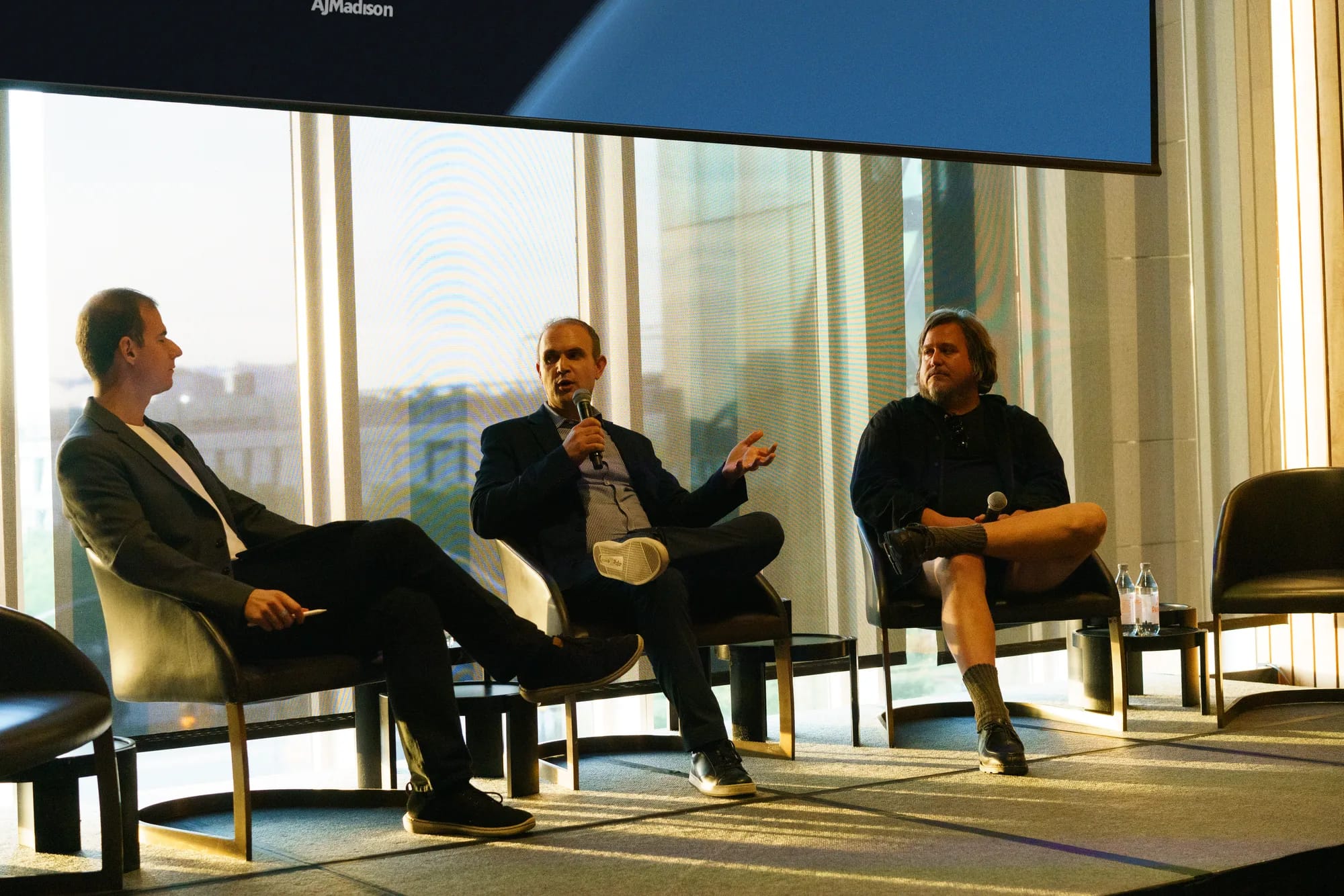 A moderator and two panelists on stage during the panel on value beyond the product
