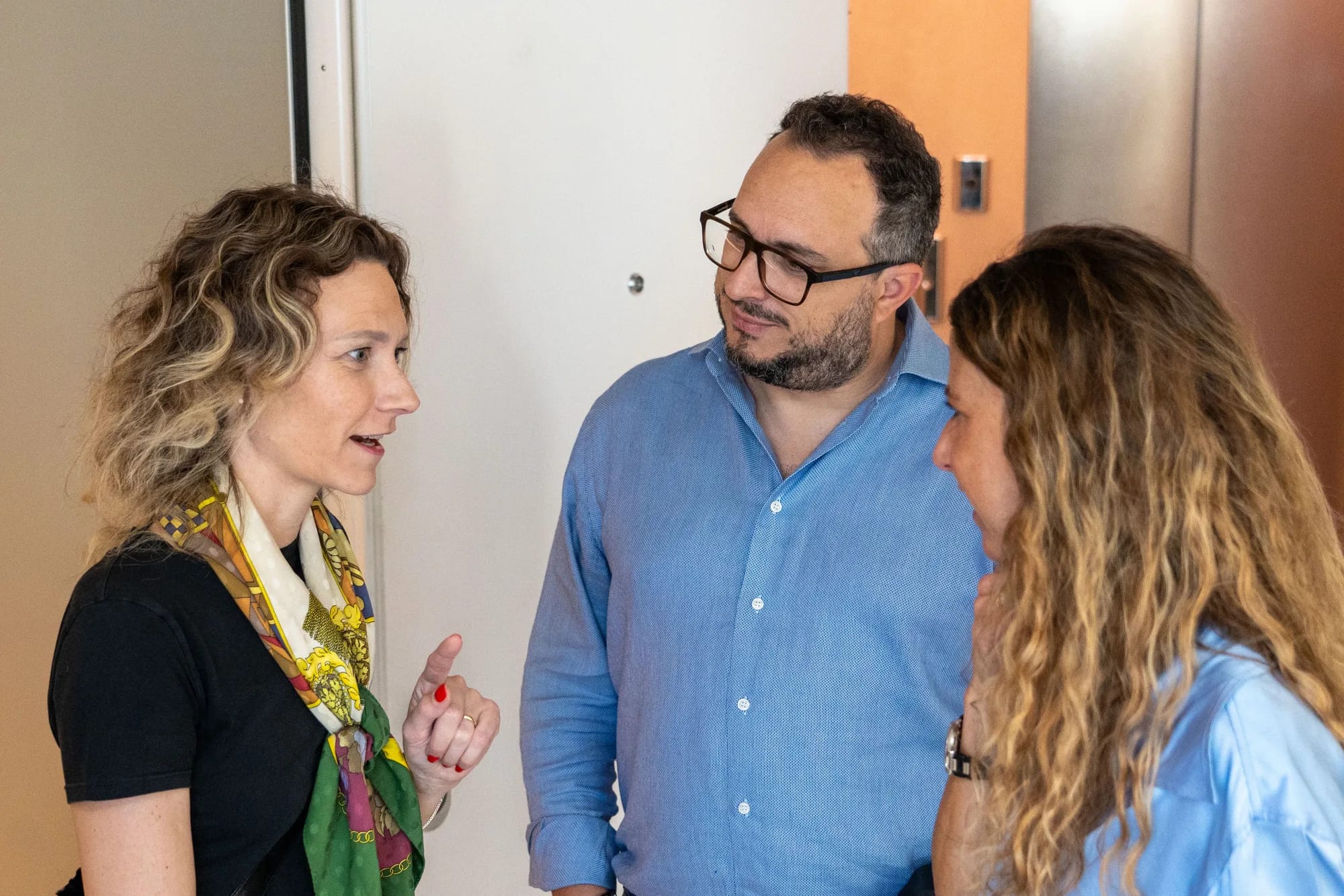 Three guests talk in a small group before the roundtable begins