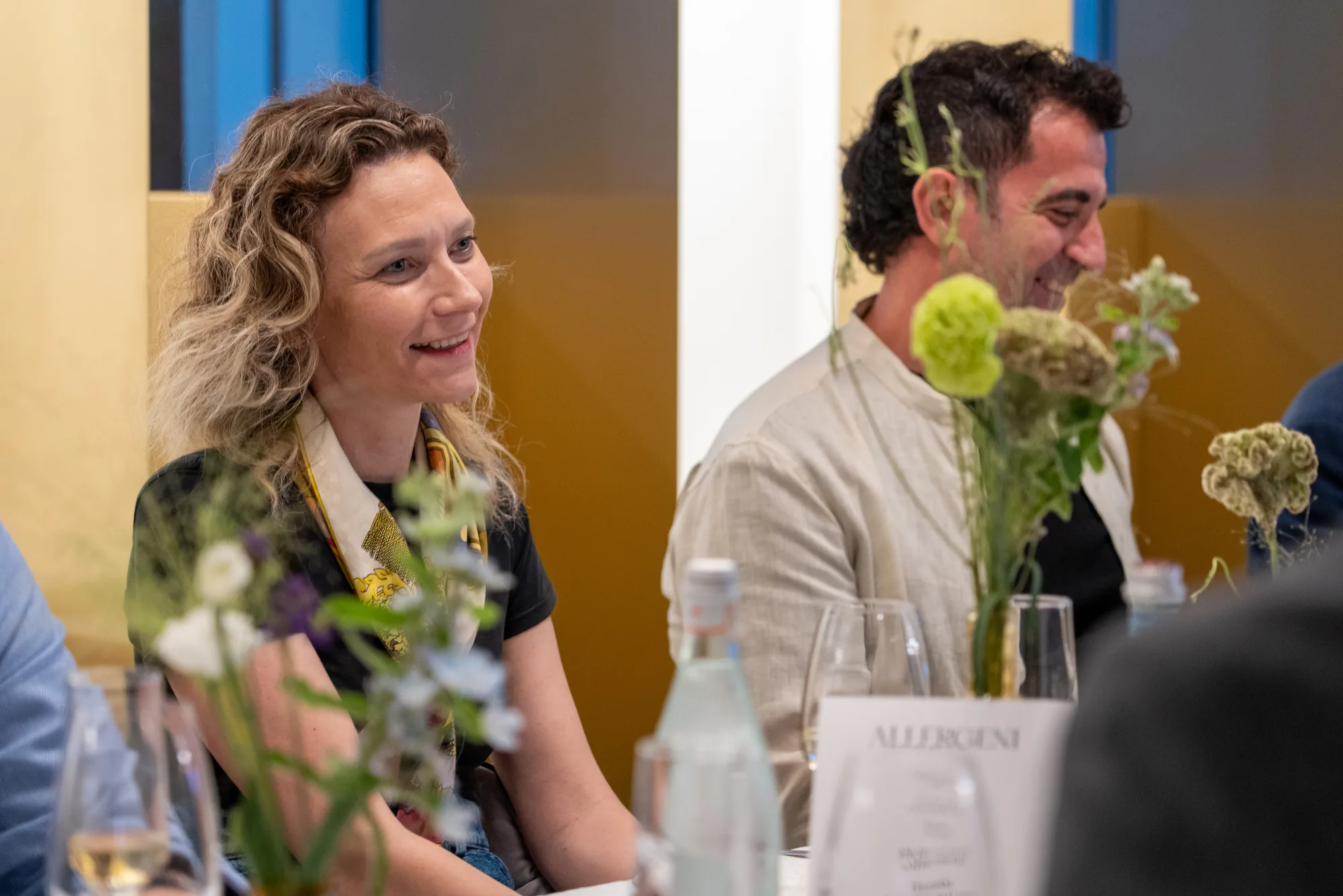Two guests smile as they listen during dinner