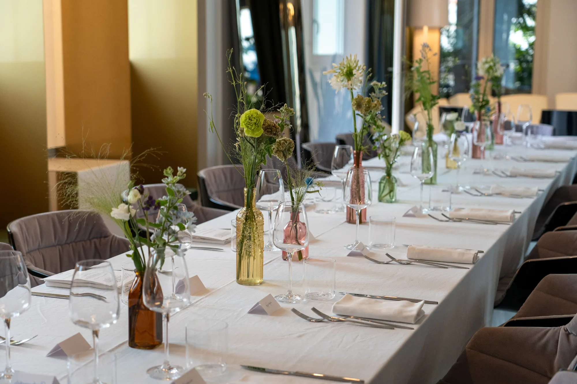Place settings and small bottle vases of wildflowers along the dinner table