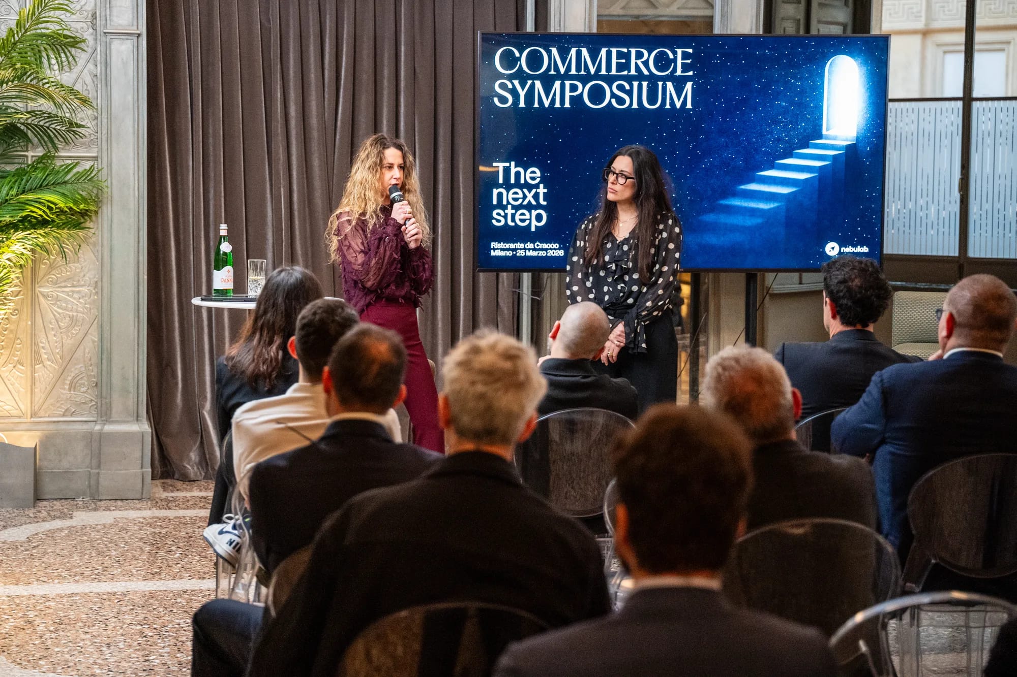 Two hosts opening the event in front of the Commerce Symposium title slide