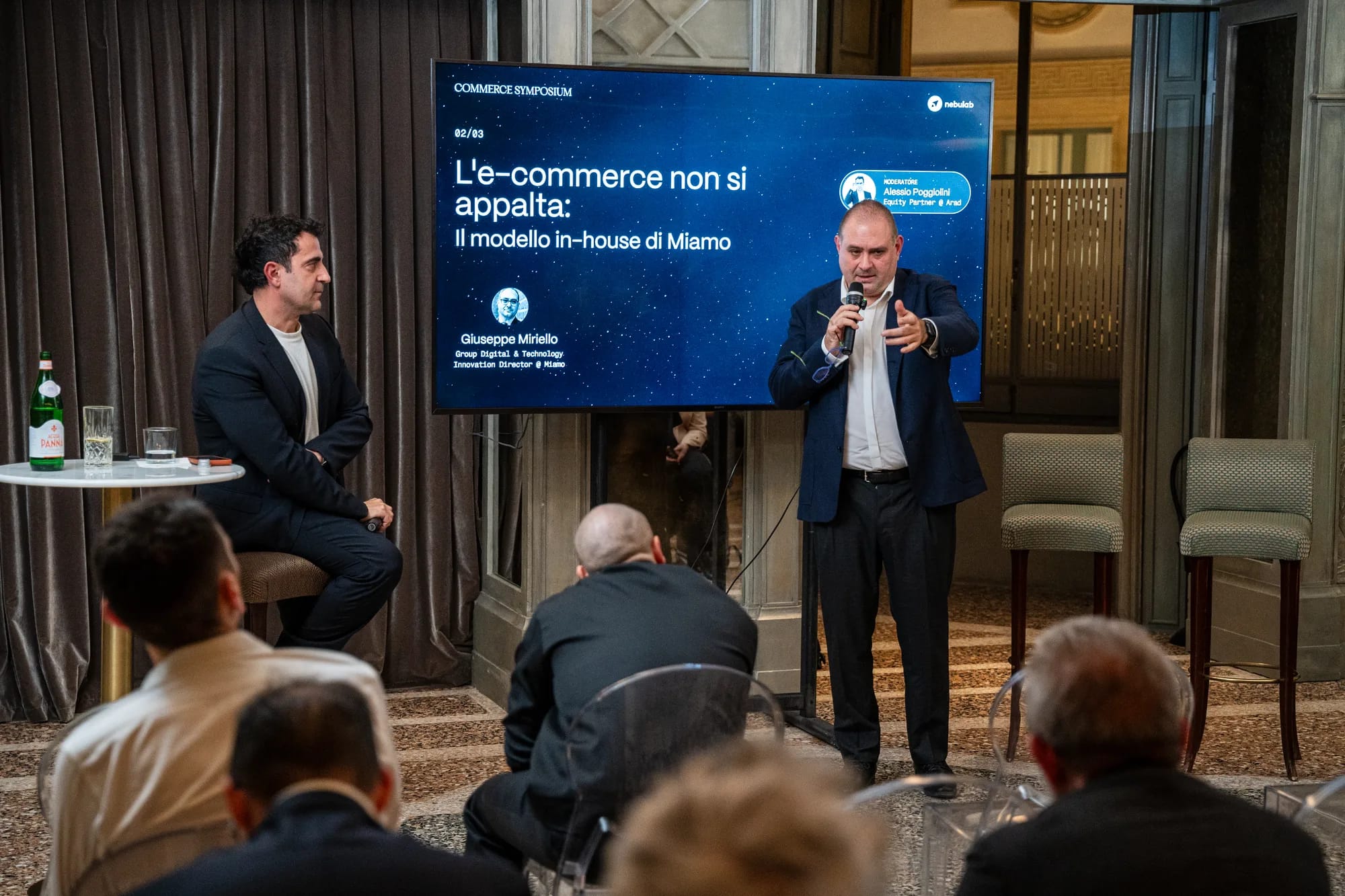 Speaker with a microphone and a seated panelist during the Miamo in-house roundtable