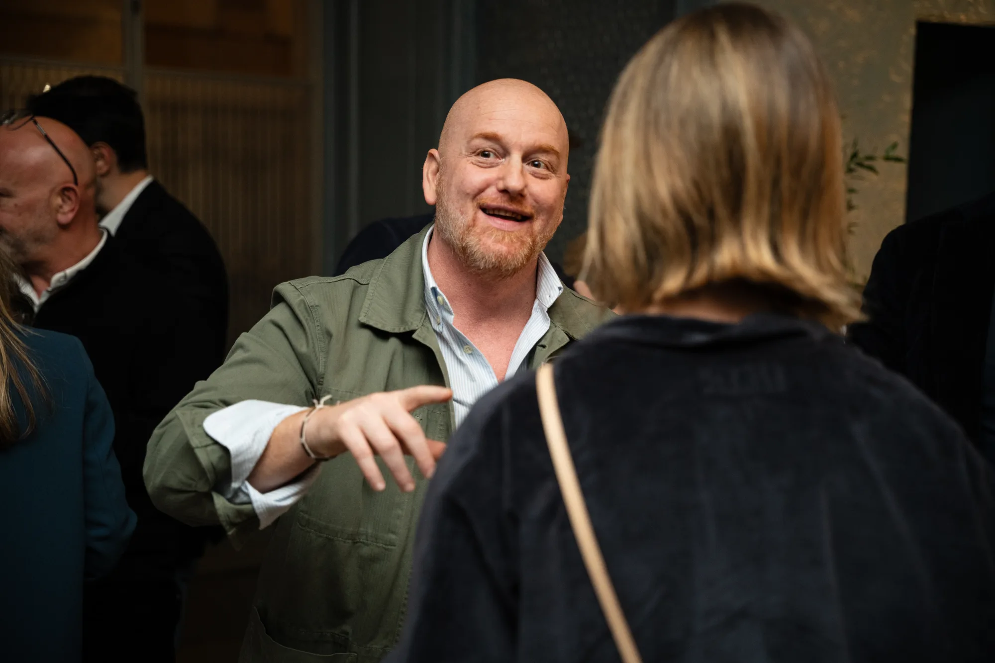 Guest in a green jacket chatting animatedly during the aperitivo