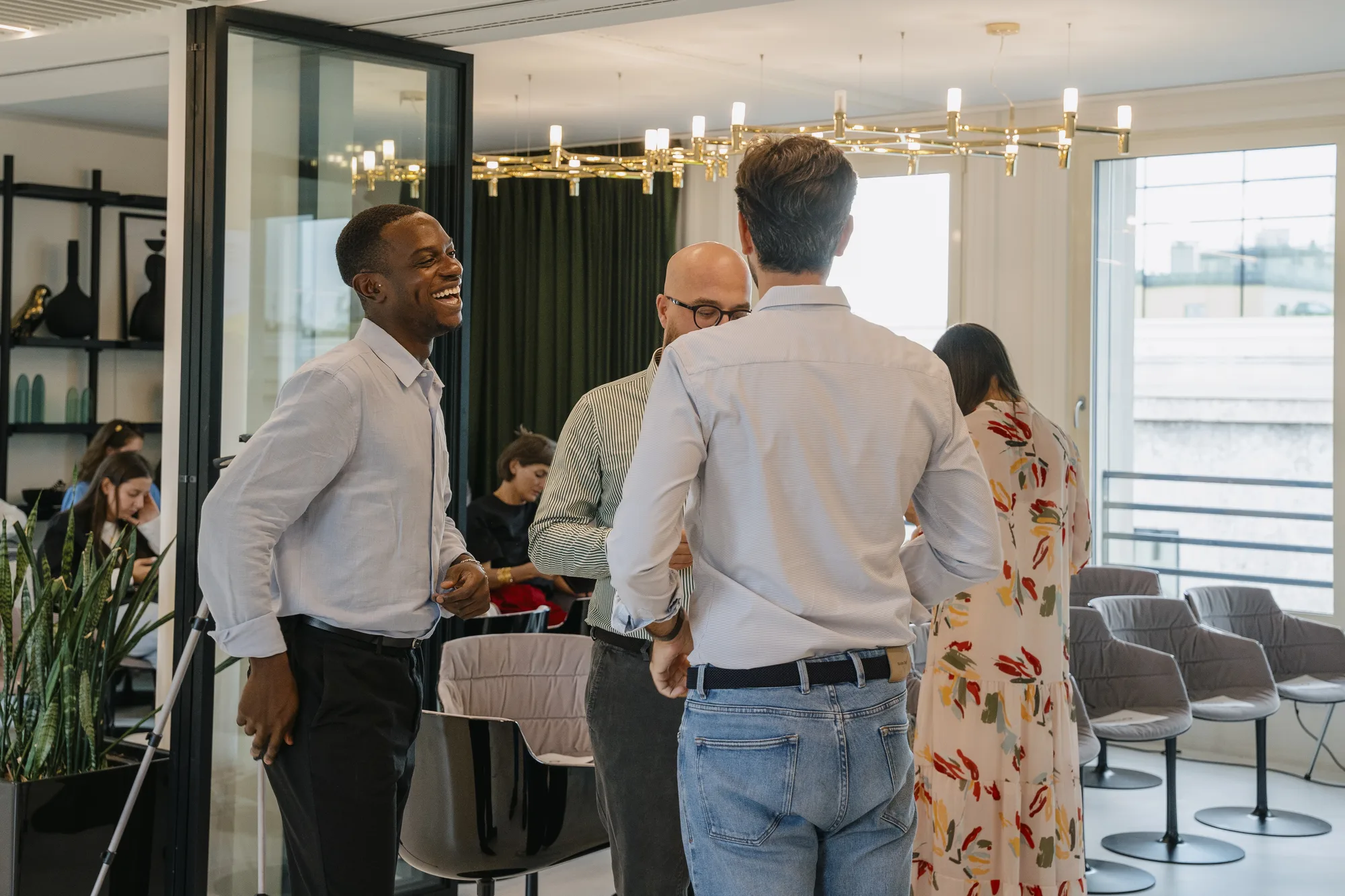 Attendees chat and laugh in a lounge with brass chandeliers before the talks