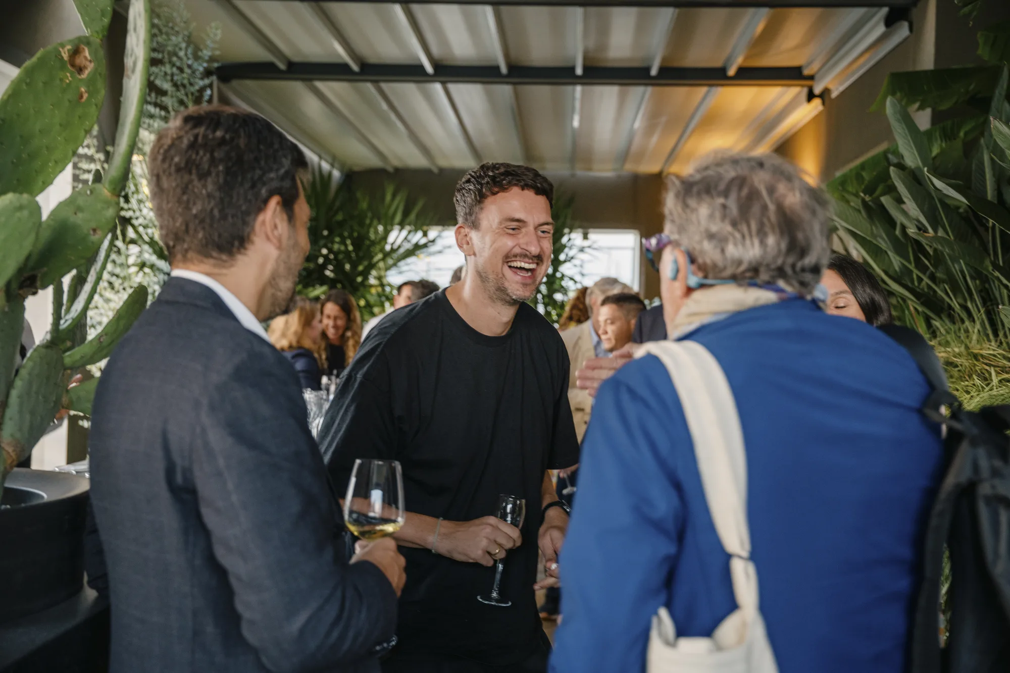 Guests laugh over glasses of wine on the plant-filled terrace