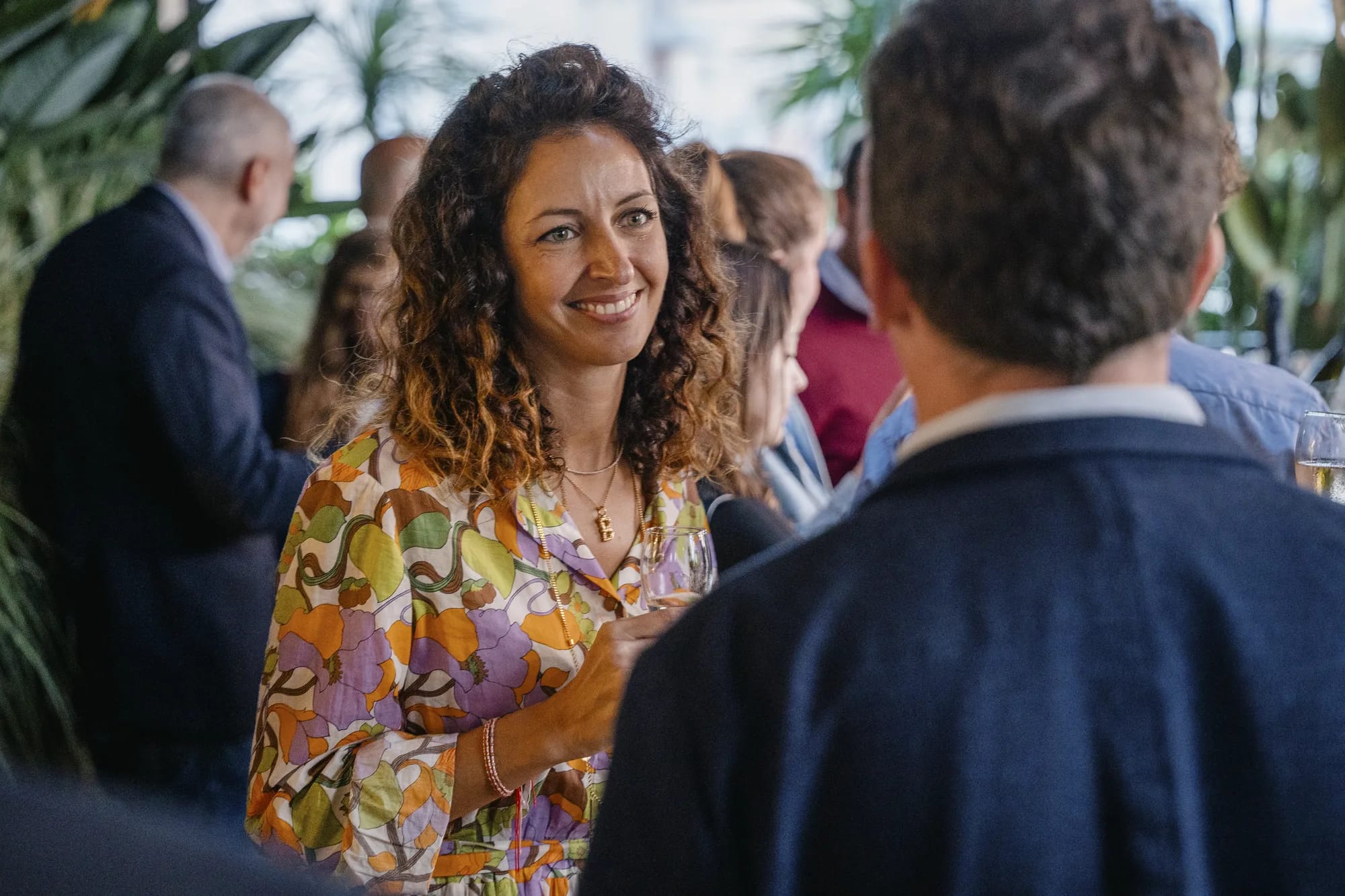 A guest smiles holding a glass of wine during the evening drinks