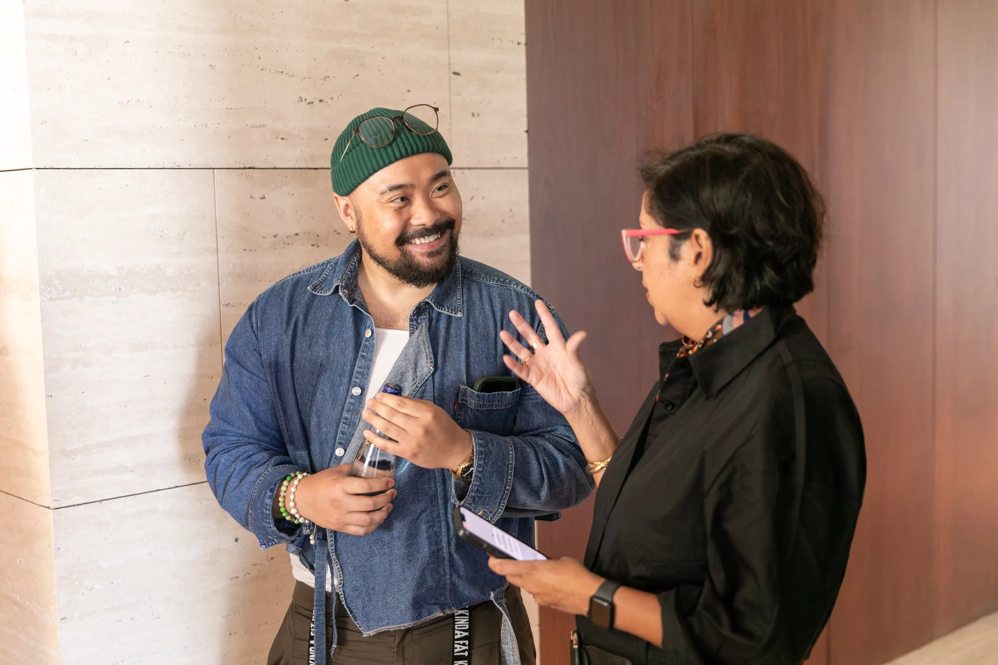 Two attendees chatting by a travertine wall during check-in