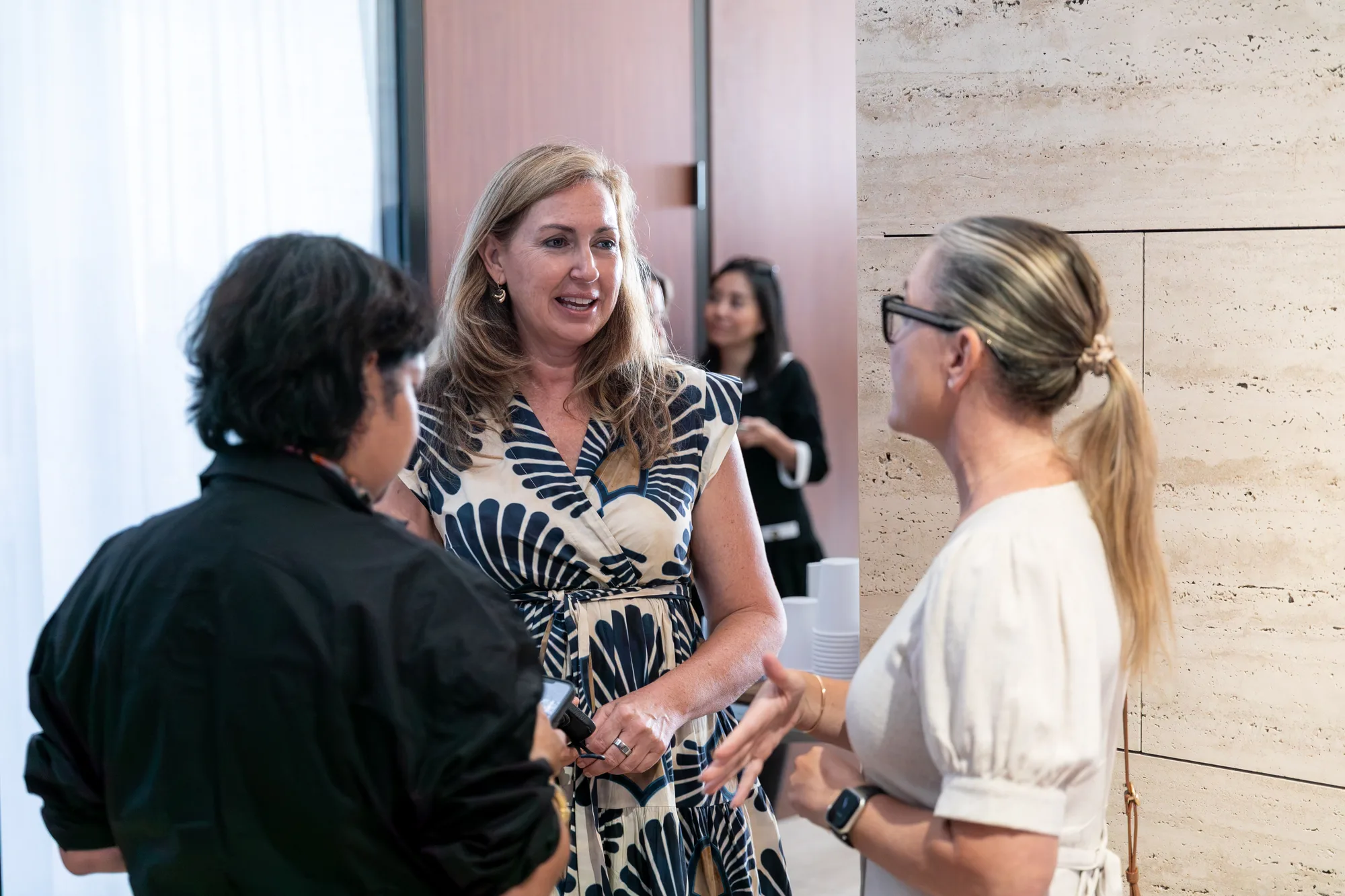 Three attendees deep in conversation before the program starts