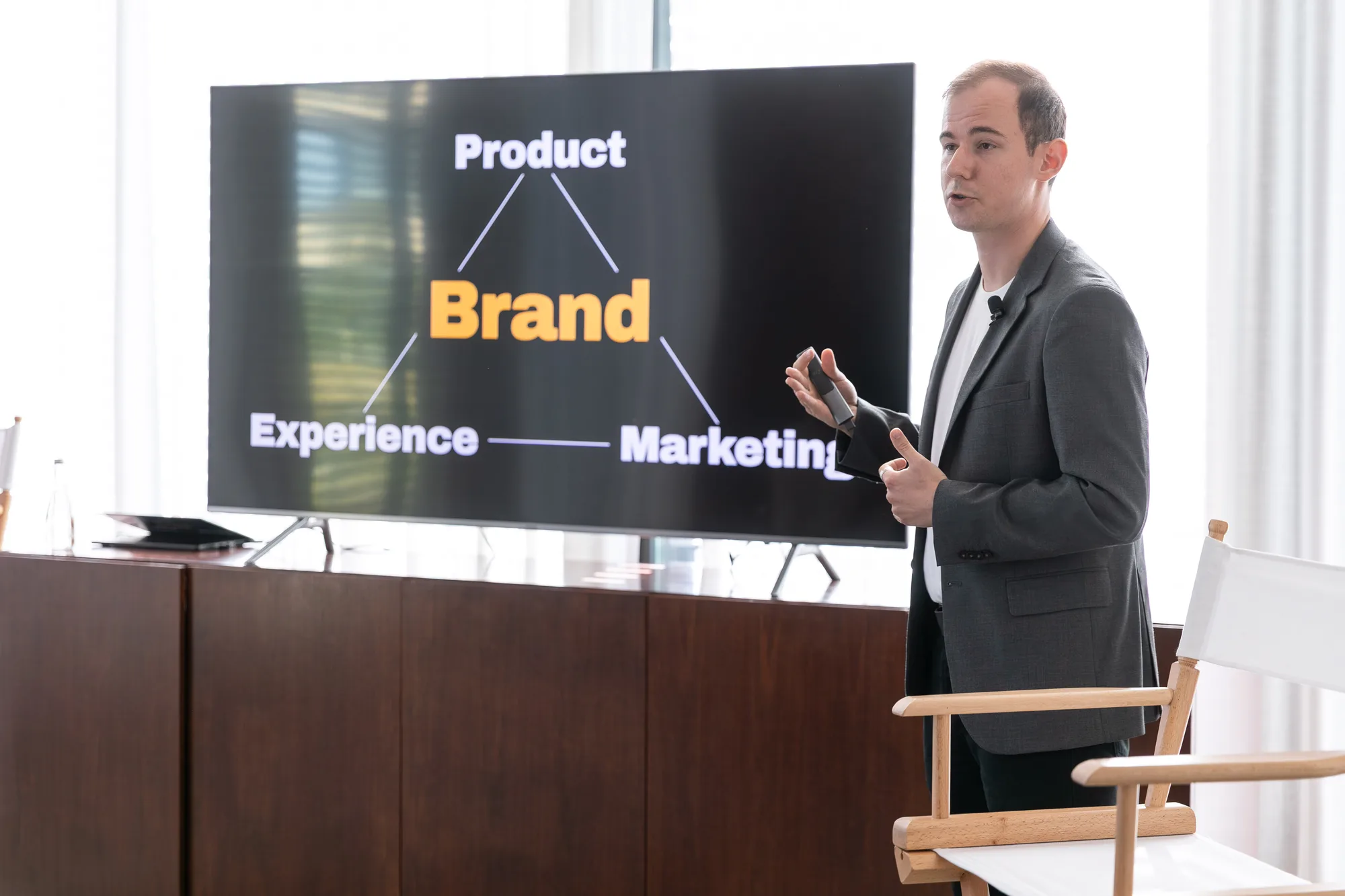 A speaker presents a slide linking brand to product, experience and marketing