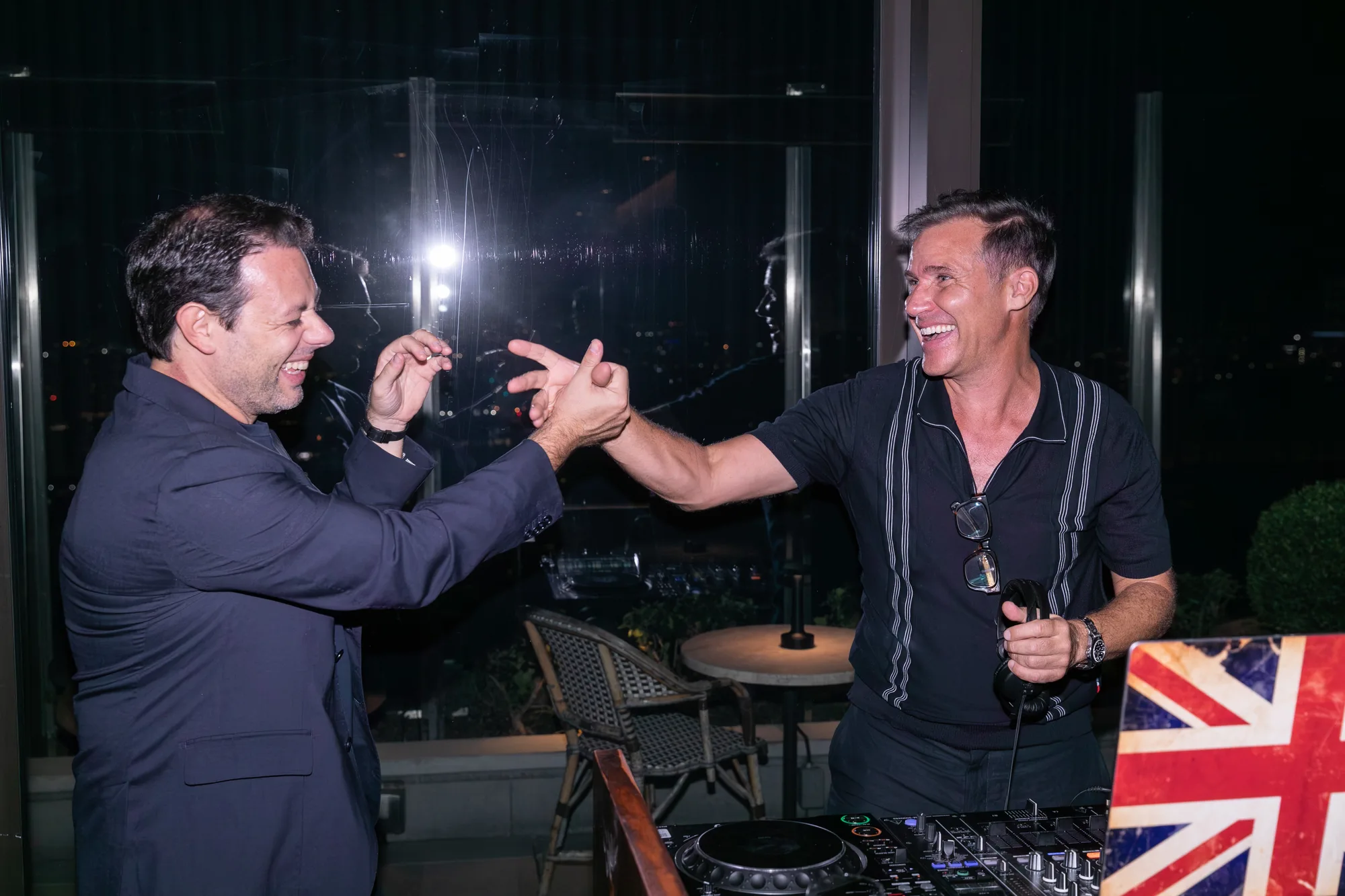 Two guests laughing beside the DJ booth at the afterparty